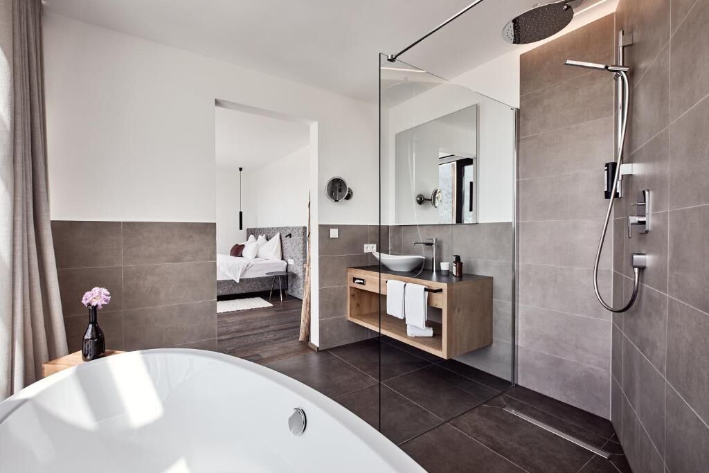 Ein modernes Badezimmer mit Badewanne, Dusche, Waschtisch mit Spiegel und Toilette.