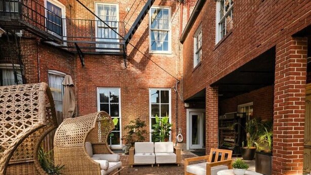 A courtyard with wicker furniture, a fire pit, and brick flooring. - Serenité King Studio+Sleeper Sofa | Near JHU & DT (Baltimore)