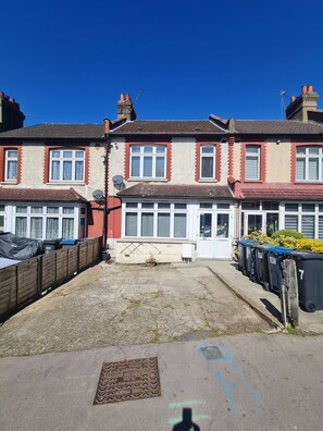 A residential building with a garage, a satellite dish, and a row of black bins. - Best Mattress to Take the Strain in London (London)