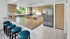 A modern kitchen with a central island, bar stools, stainless steel appliances, and wooden cabinets. - Scottsdale Oasis Diving Pool, Game Room & 4BR Near Old Town & Mayo Clinic (Scottsdale)