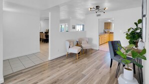 A spacious living area with a wooden floor, a dining area, and a kitchen with wooden cabinets. - Scottsdale Oasis Diving Pool, Game Room & 4BR Near Old Town & Mayo Clinic (Scottsdale)