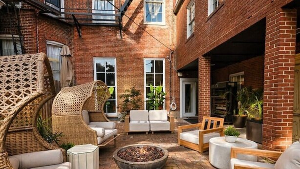 A courtyard with brick flooring, wicker furniture, and a fire pit.