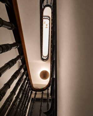 A staircase with a wooden handrail and a metal railing, leading to a room with a round light fixture. - Amour Luxury King Suite w/ Soaking Tub - Boutique Hotel Near Johns Hopkins & DT (Baltimore)