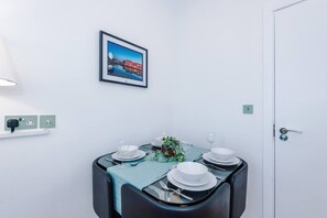 A dining area with a table set for four, a framed picture on the wall, and a door to the right. - 4 Guests | 1 Double bed and Sofa Bed (Merseyside)