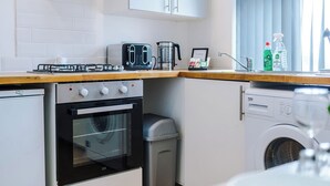 Eine kleine Küche mit Gasherd, Toaster, Wasserkocher und Waschmaschine.