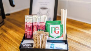 Eine Auswahl an Kaffeepads, Teebeuteln und PG Tips Teebeuteln auf einer Holztischplatte.