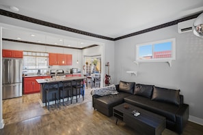 Eine moderne Küche mit roten Schränken, ein Essbereich mit einer schwarzen Ledersofa und Blick auf die Stadt durch ein Fenster.