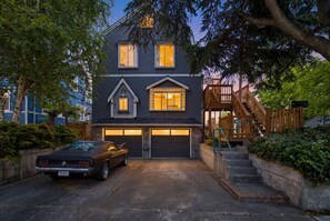 Ein zweistöckiges Haus mit Garage, Treppe und einem parkenden Auto.