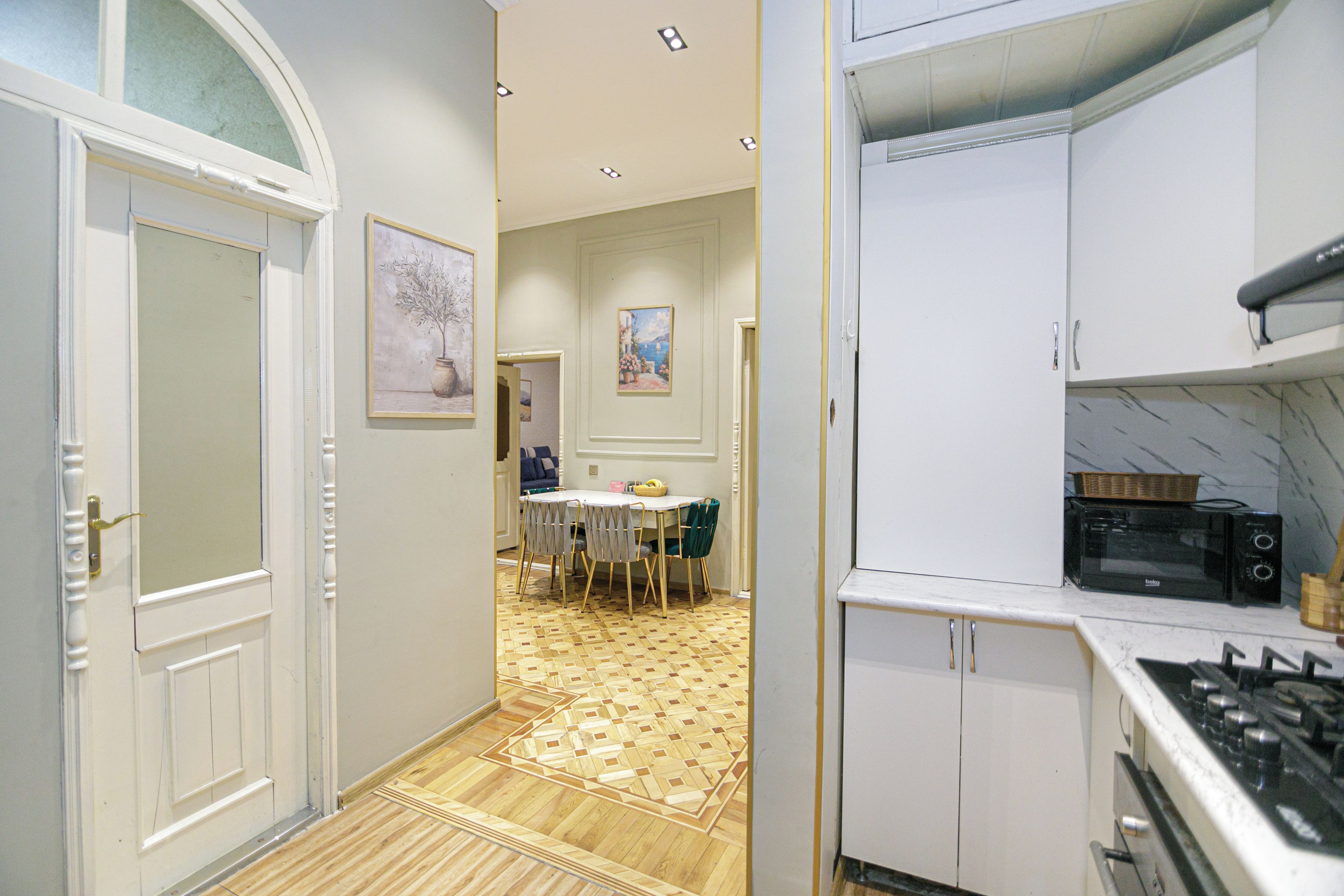 A kitchen with a microwave, stove, and a dining area with chairs and a table.