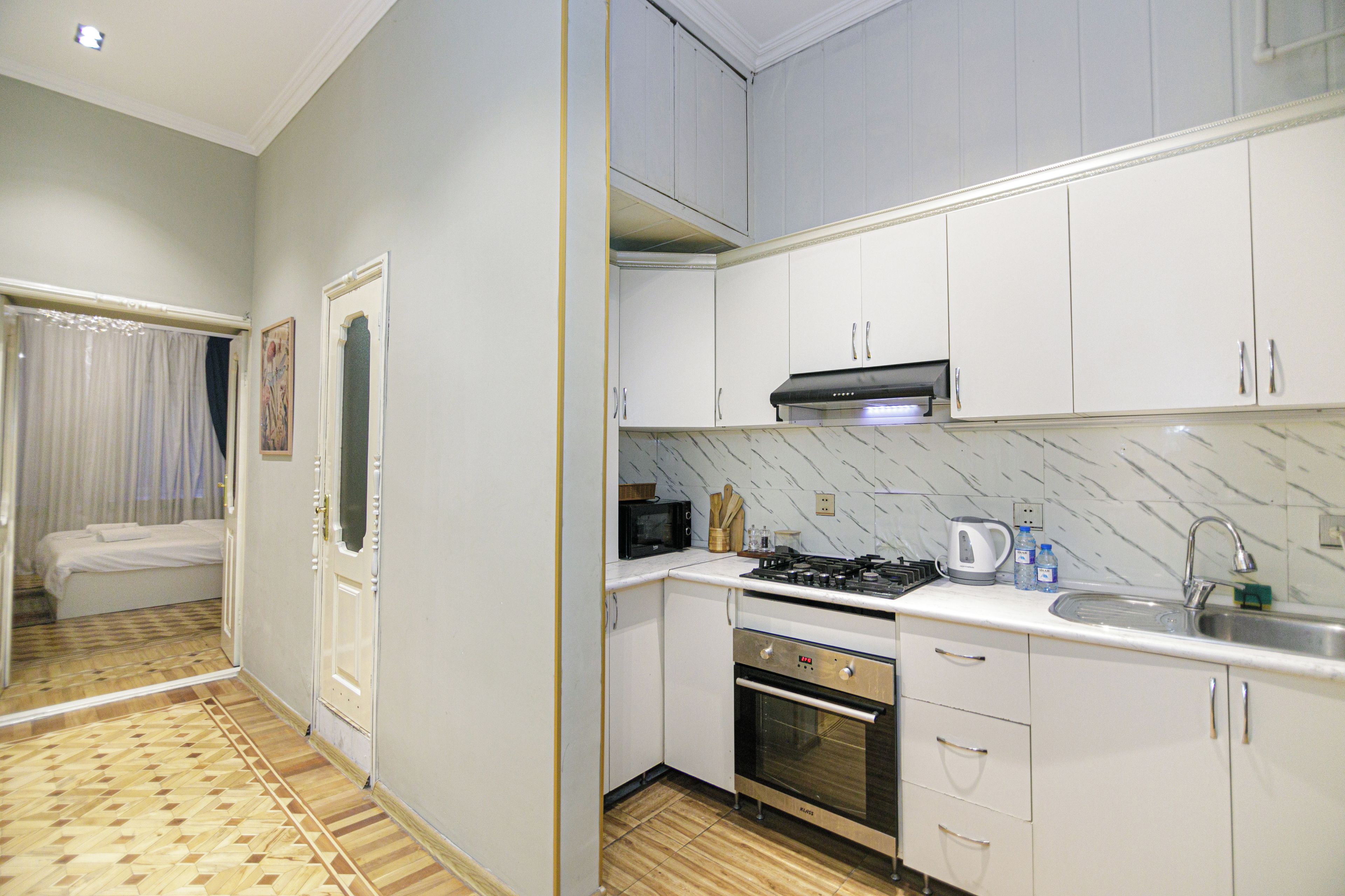 A compact kitchen with white cabinets, a gas stove, a microwave, and a sink.