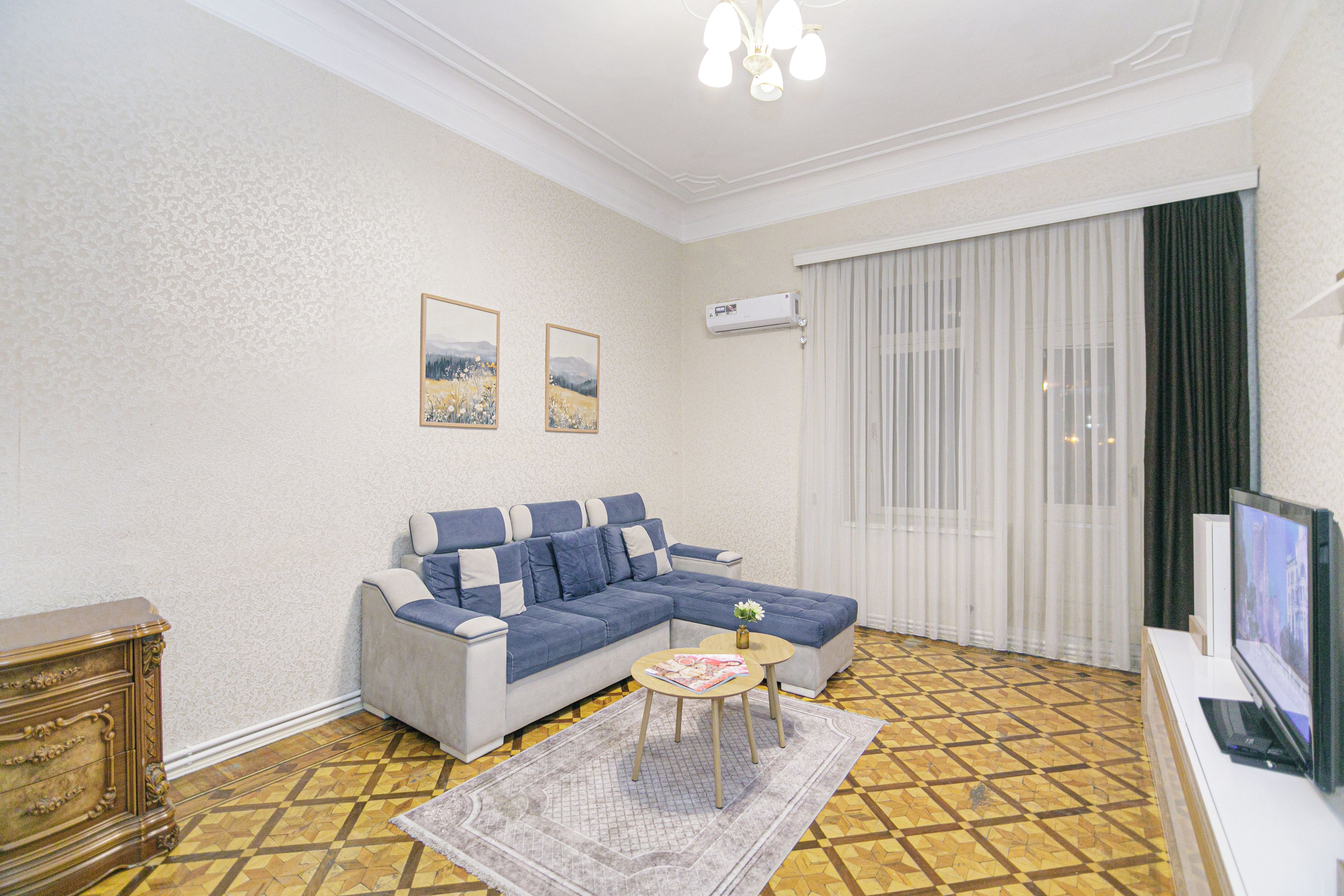 A living room with a sofa, a coffee table, a TV, and a patterned floor.