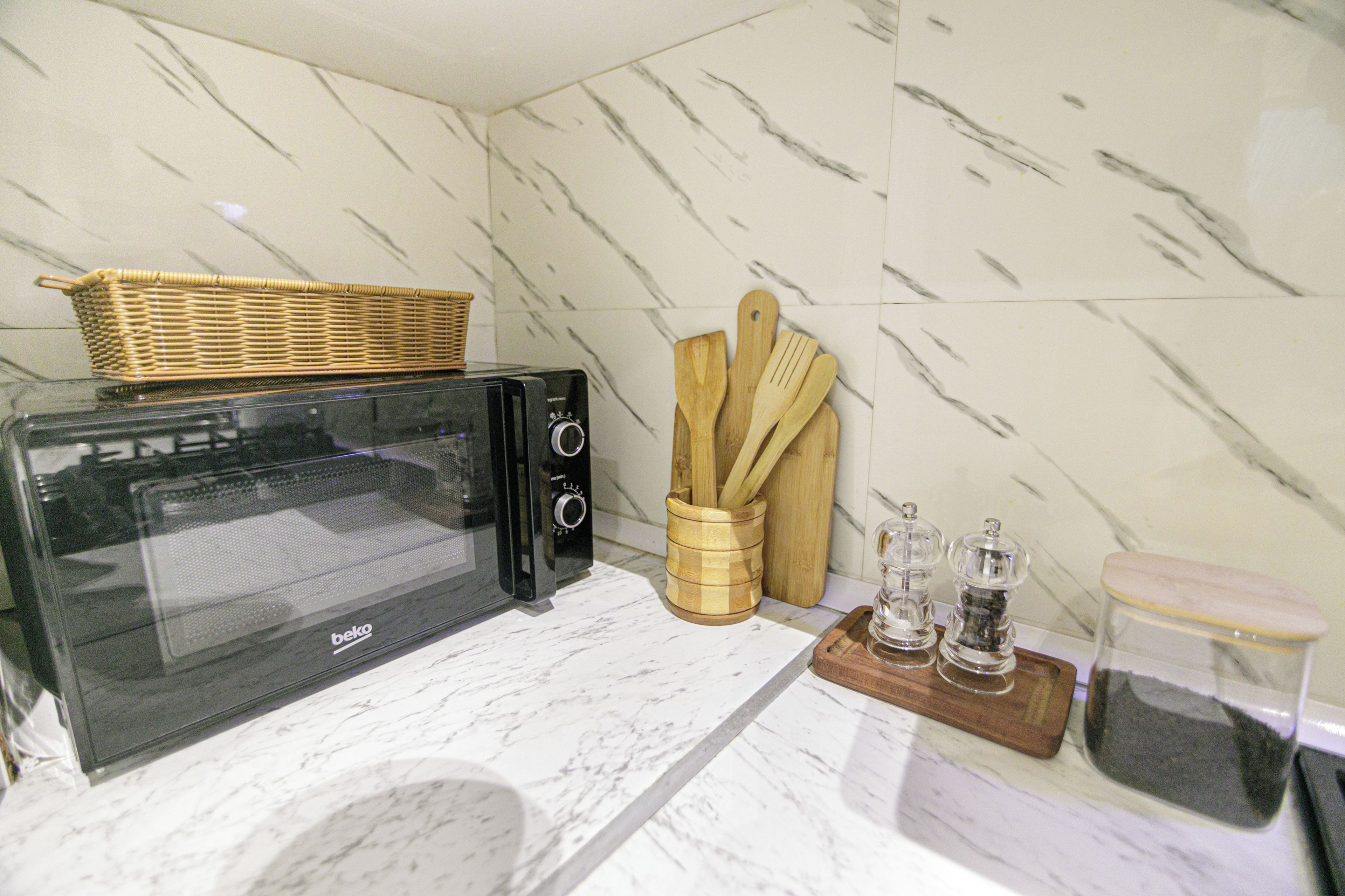 A kitchen with a microwave, wooden utensils, and a spice rack.