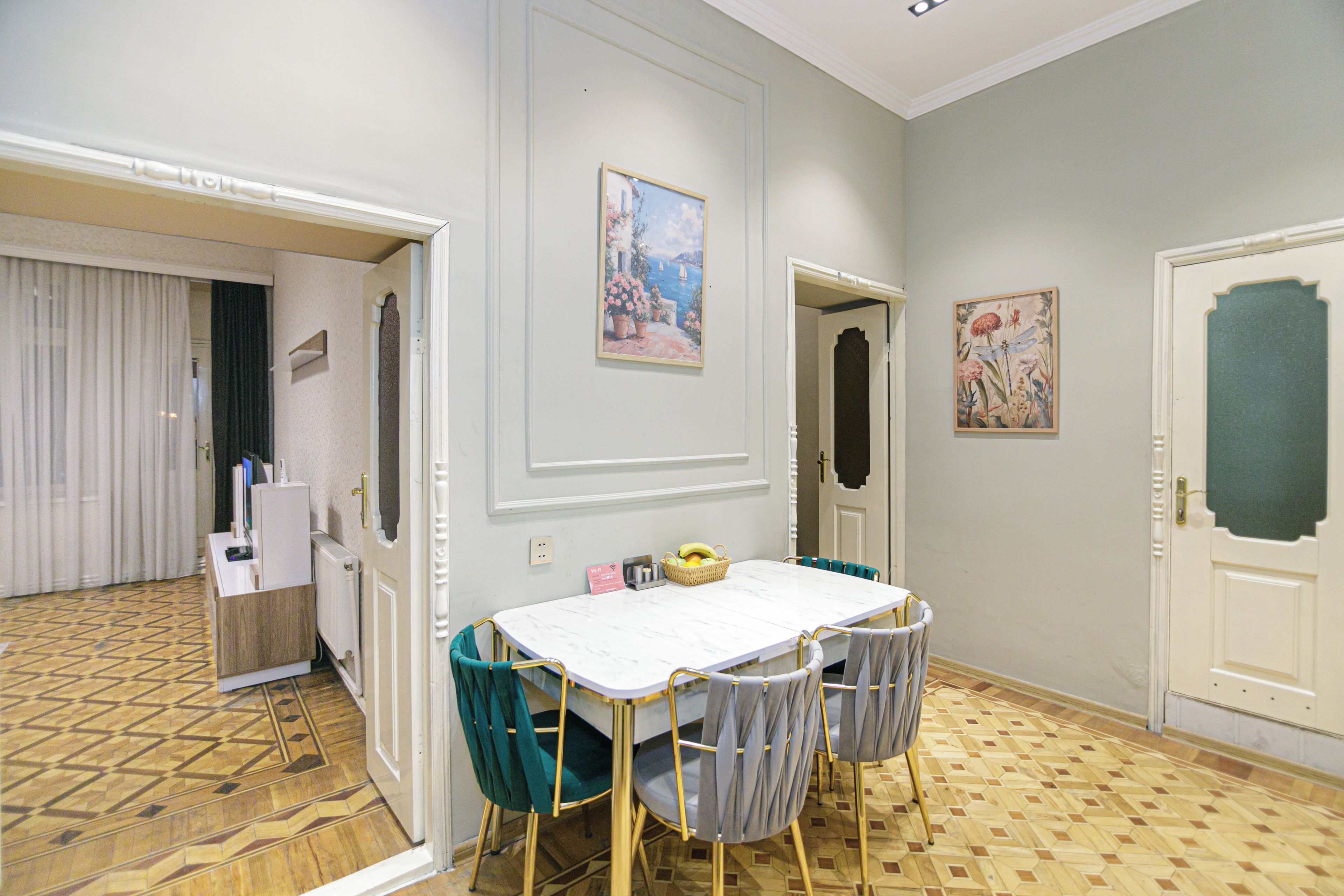 A dining area with a table and chairs, a painting on the wall, and a patterned floor.