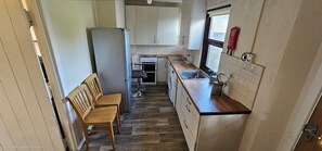 A compact kitchen with white cabinets, a built-in oven, a sink, and a window. - Cozy Waterford 2-bed Cottage, Sleeps 4 With Views (Waterford)