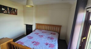 A bedroom with a bed, a nightstand, a lamp, and a door. - Cozy Waterford 2-bed Cottage, Sleeps 4 With Views (Waterford)