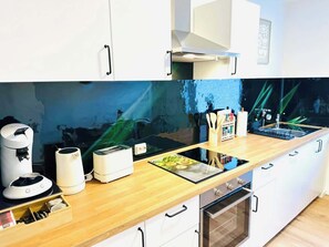 Moderni keittiö, jossa on sisäänrakennettu uuni, kahvinkeitin ja leivänpaahdin.