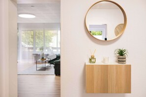 Un intérieur moderne avec une console en bois, un miroir rond, une petite plante et une bougie.