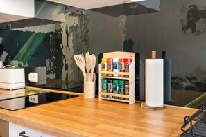 Une cuisine dotée d’un plan de travail en bois, d’un porte-épices, d’un support à essuie-tout et d’un pare-feu avec une surface réfléchissante.