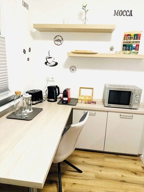 Eine Küchenzeile mit Mikrowelle, Kaffeemaschine und einer Wanddekoration mit Kaffeemotiv.