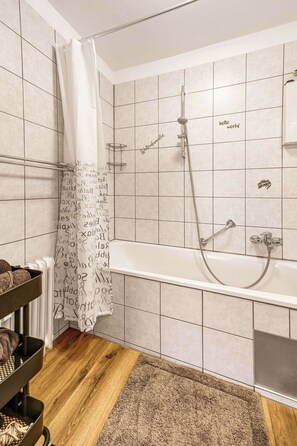 Ein Badezimmer mit Badewanne, Dusche und Handtuchhalter.