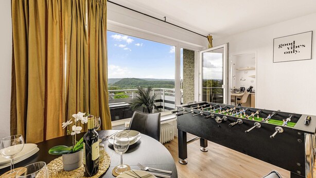 A modern room with a foosball table, a dining table set for two, and a view of the outdoors.