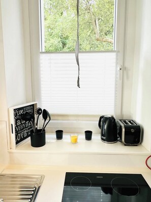 Eine Küche mit Fenster, Wasserkocher, Toaster und einem Schild mit motivierenden Sprüchen.