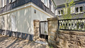 A house with a stone wall, a metal gate, and a paved driveway.