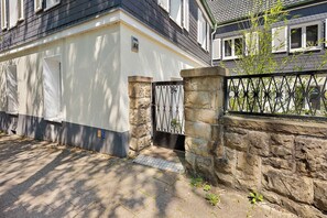 Une maison avec un mur en pierre, un portail en métal et une allée pavée.