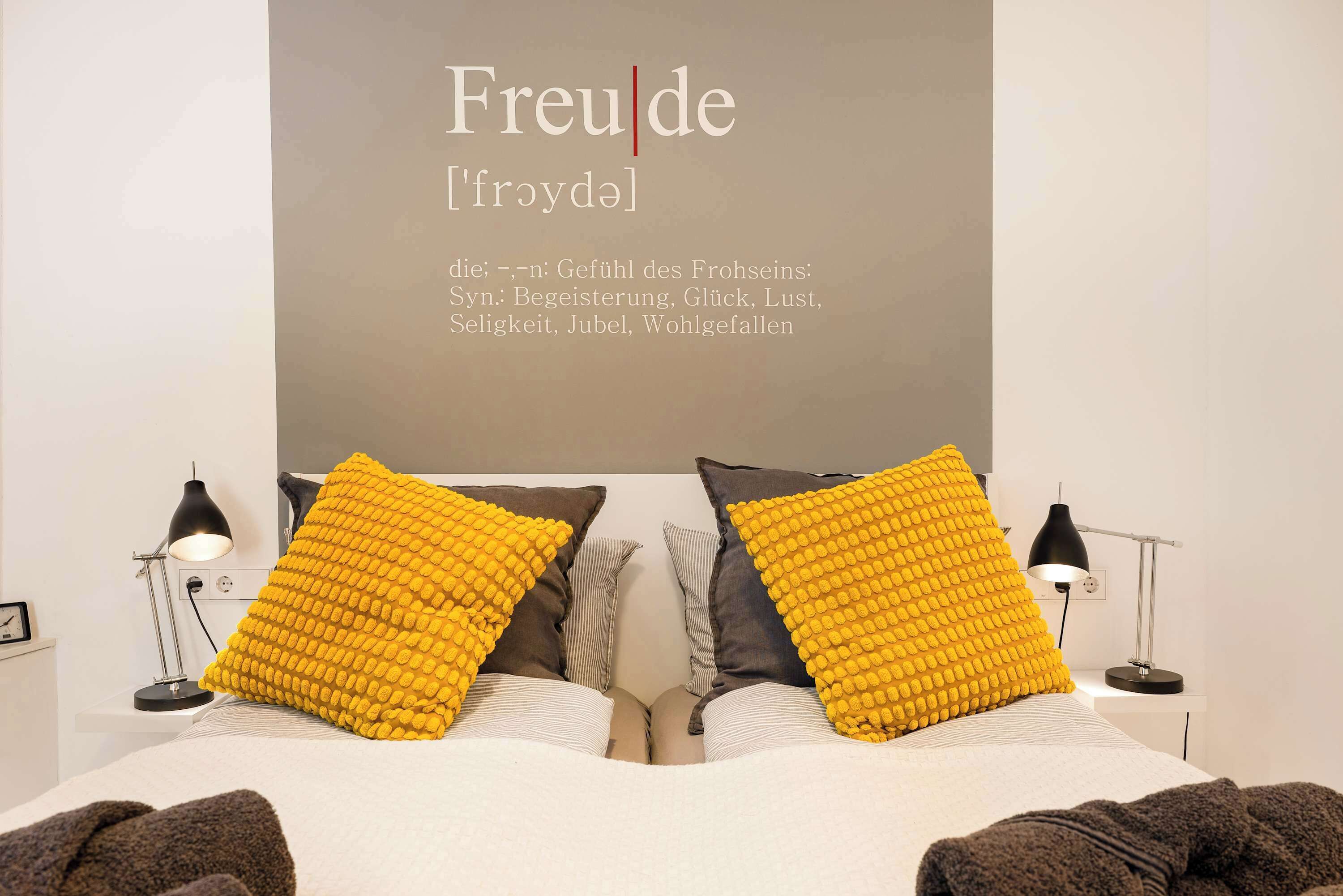 Ein Schlafzimmer mit einem Bett, zwei Lampen und einer Wand mit Schrift.