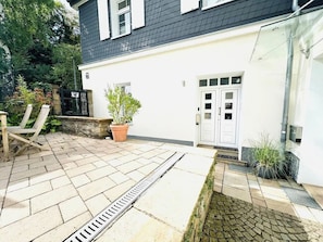 Een huis met een terras, een witte deur en een raam.
