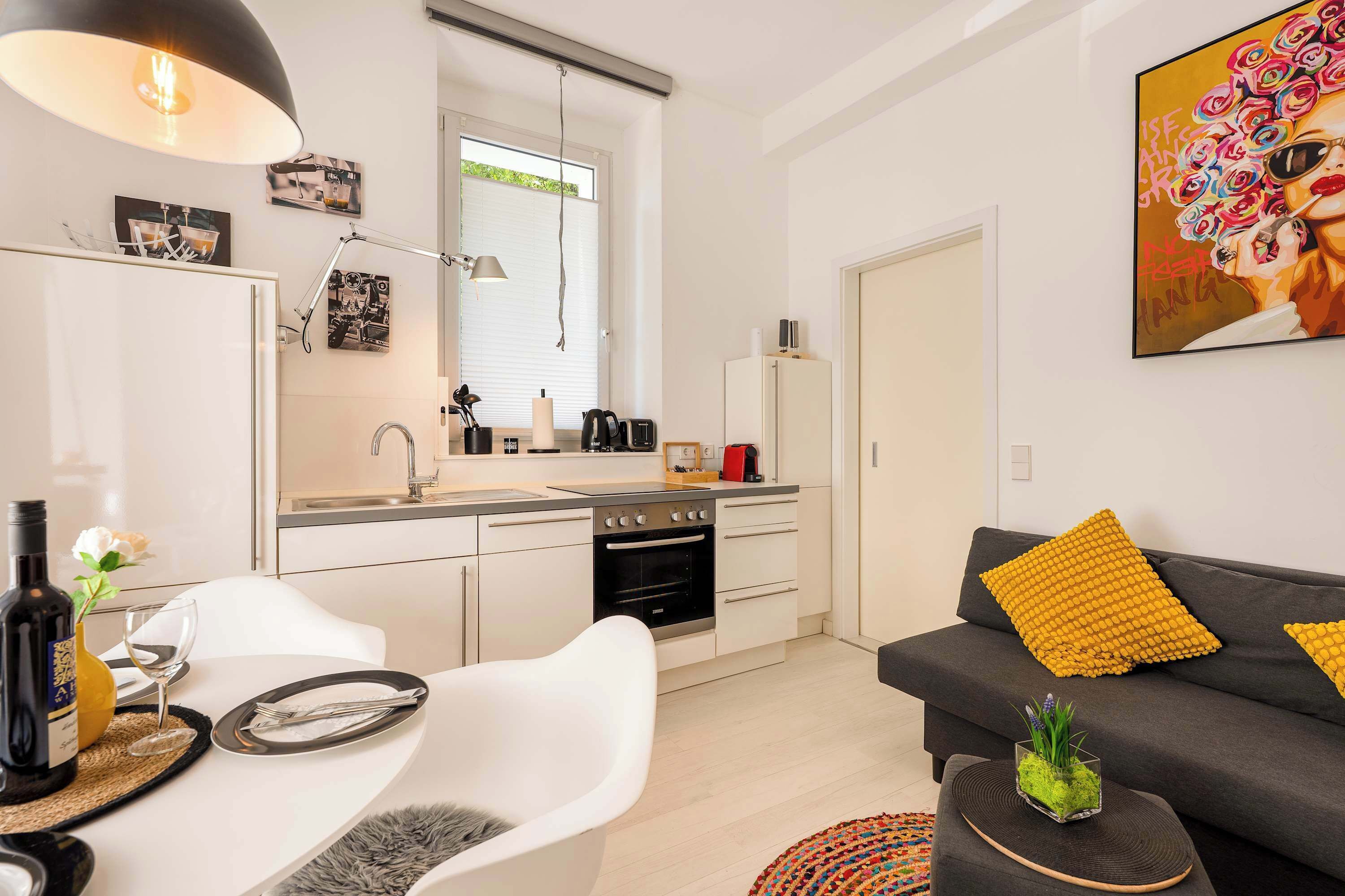 Eine moderne Küche mit Essbereich, einem Sofa mit gelben Kissen und einem Bild an der Wand.