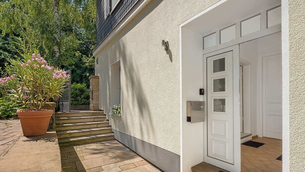 A house with a white exterior, a front door, and a small set of steps leading to the entrance.