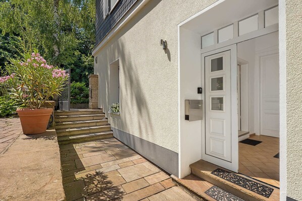 Une maison à l’extérieur blanc, avec une porte d’entrée et un petit escalier menant à l’entrée.