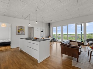 Eine moderne Küche mit Kochinsel, Essbereich mit Ausblick und einer gemütlichen Sitzecke.