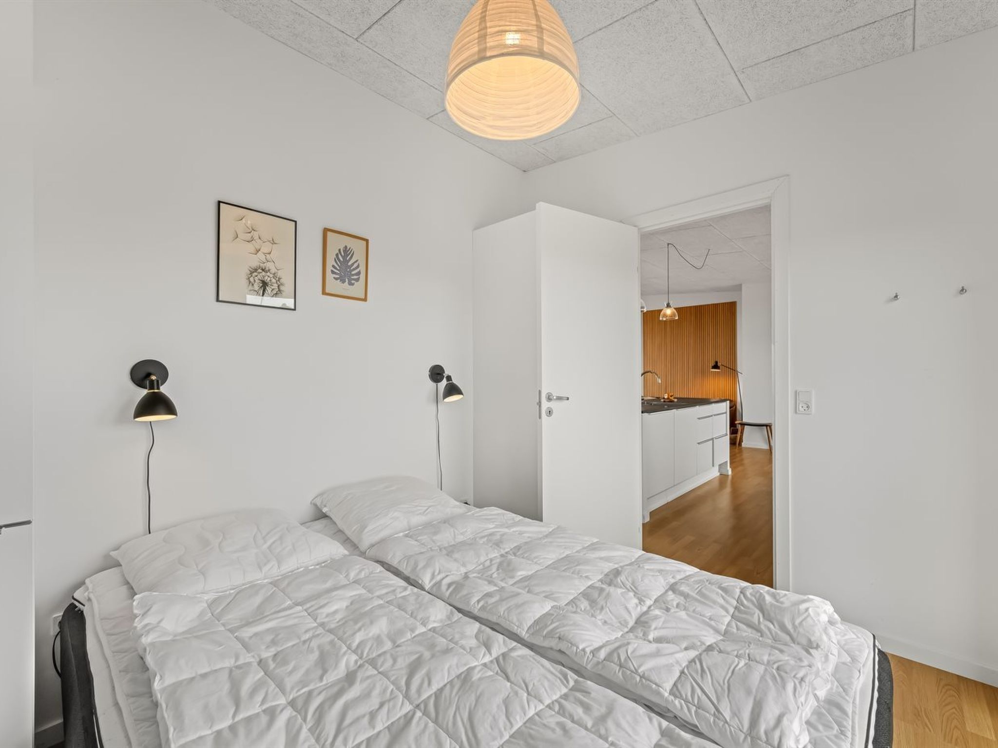 Une chambre à coucher avec un lit, des lampes de chevet et un luminaire suspendu.
