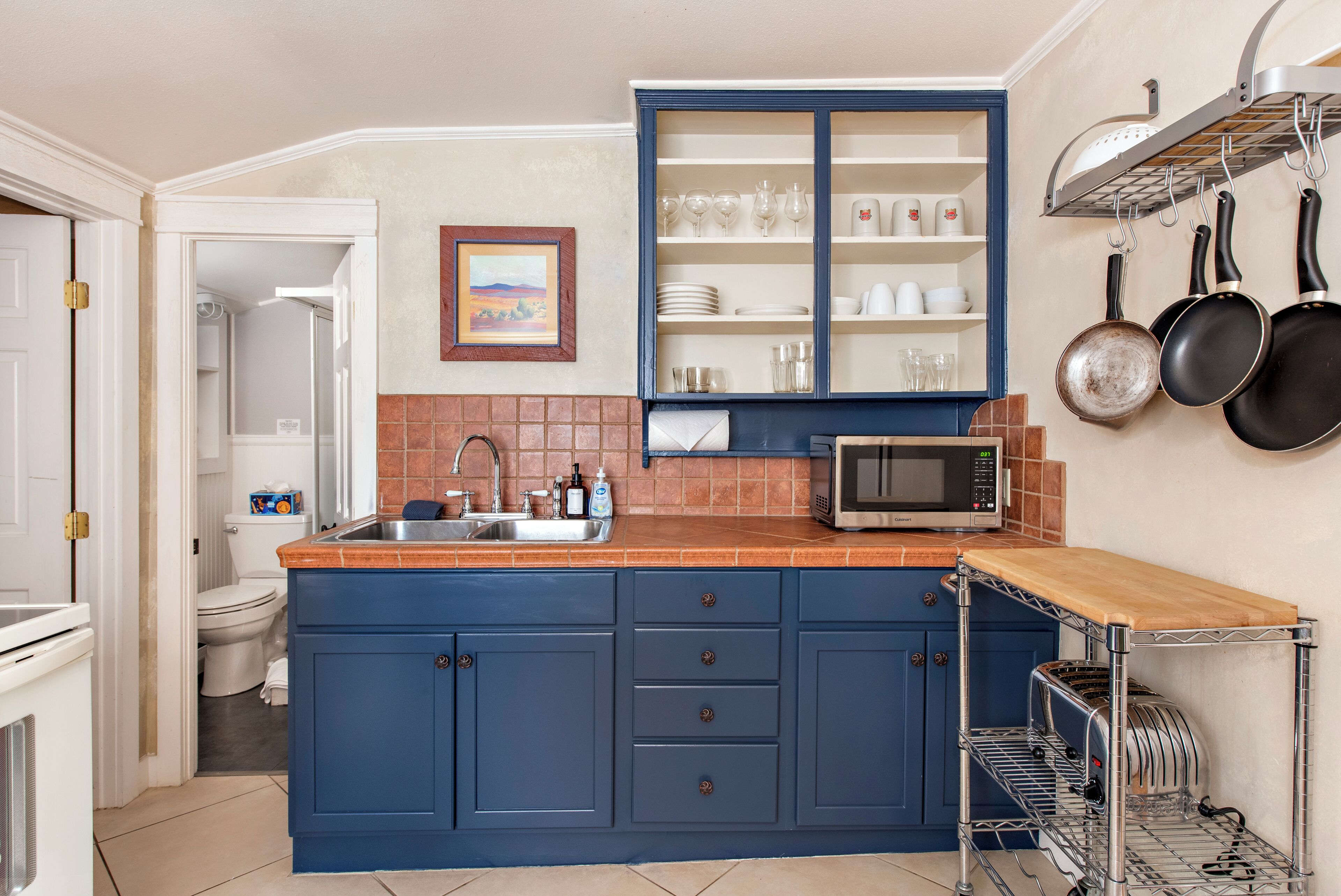 A kitchen with a blue cabinet, a microwave, and a dish rack.