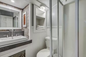 Ein Badezimmer mit einem weißen Waschbecken, einer Toilette und einer Duschkabine aus Glas.