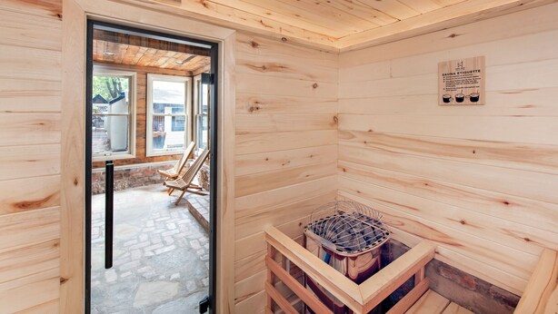Uma sala de sauna com paredes de madeira, um banco de sauna e um aquecedor.