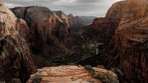 Un paisaje de cañón rocoso con formaciones de roca estratificadas y un sendero serpenteante.