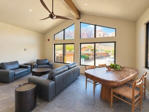 A spacious living area with a large sofa, a dining table with chairs, and a ceiling fan. - Purple Sage Place (Springdale)