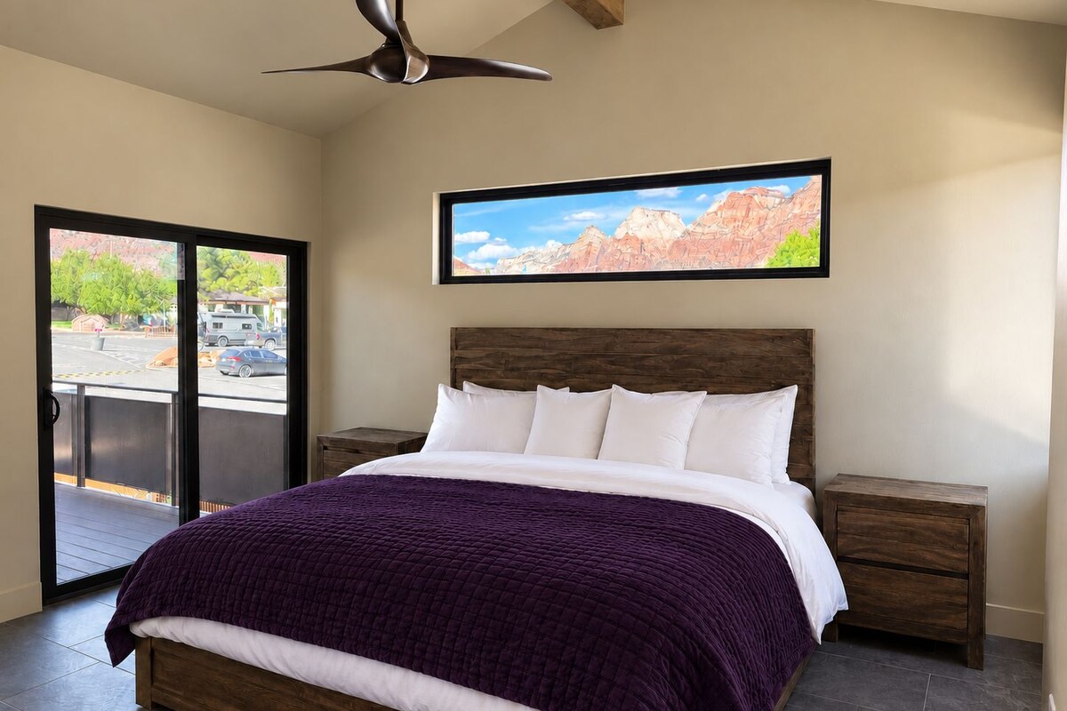 A bedroom with a bed, a nightstand, a ceiling fan, and a window with a view of the outside.
