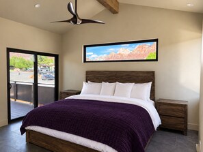 A bedroom with a bed, a nightstand, a ceiling fan, and a window with a view of the outside. - Purple Sage Place (Springdale)