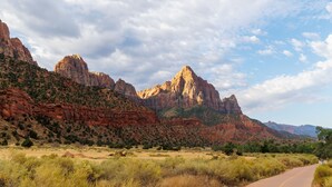 Una carretera que atraviesa un paisaje desértico con formaciones rocosas rojas y vegetación escasa.