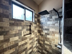 A shower with a black hose and a window above it. - Purple Sage Place (Springdale)