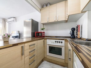A compact kitchen with a microwave, oven, and a coffee machine. - Skorpios by Interhome (Salou)