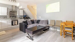 Una cucina moderna con mobili bianchi, un piano cottura integrato e un espositore per pentole a sospensione.
