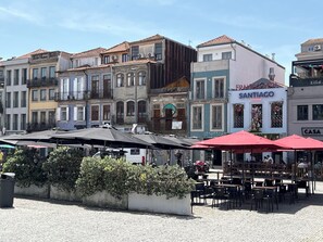 A street with buildings, outdoor seating, and a sign for 'Francesinha Santiago.' - Passos Collection 263 (Porto)