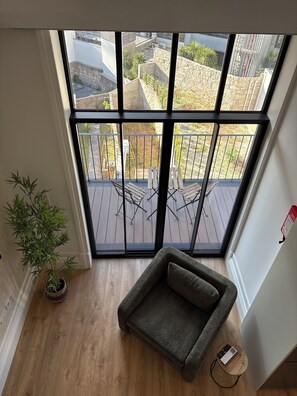 A high-rise apartment with a large window, a wooden floor, a gray sofa, and a potted plant. - Passos Collection 263 (Porto)
