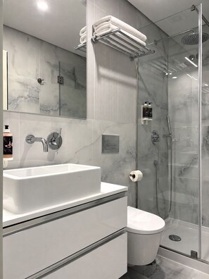 A modern bathroom with a glass shower enclosure, a white sink, and a toilet. - Passos Collection 263 (Porto)