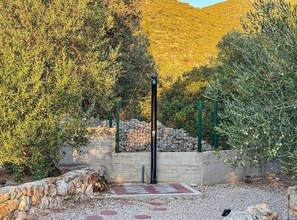 A garden with olive trees, a stone wall, and a metal fence. - Two bedroom apartment with garden (Trpanj)
